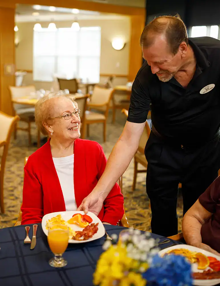Chef serving a female resident breakfast